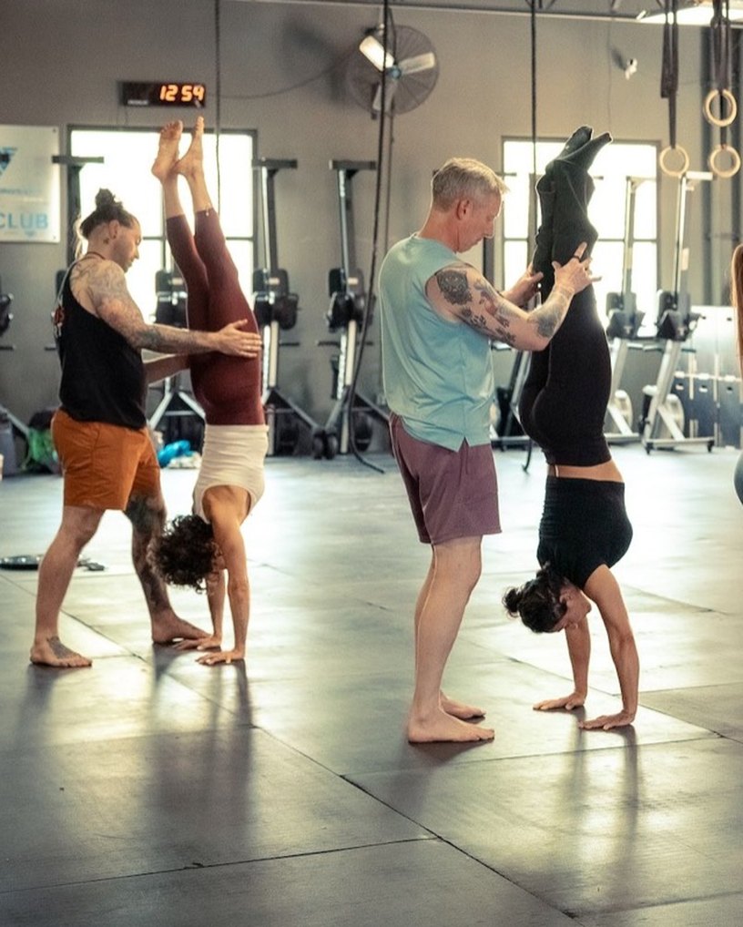 A coach spotting students as they kick up into handstands
